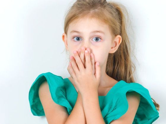 niña con un diente negro tapandose la boca tratamientos de endodoncia dentista en Gijón Clínica Dental Beatriz Vega